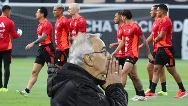 Jorge Fossati rezando, mientras los jugadores de la Selección Peruana caminan